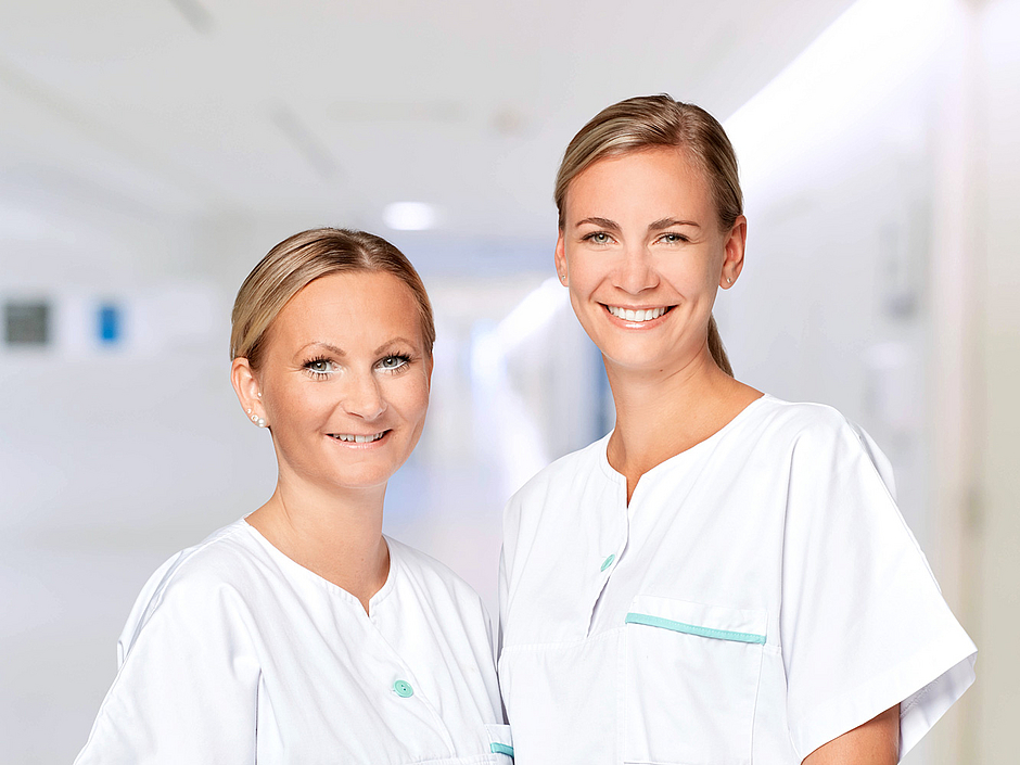 Pflegefachkräfte stehen im Klinikflur und lächeln. Pflegefachkräfte stehen im Klinikflur und lächeln.